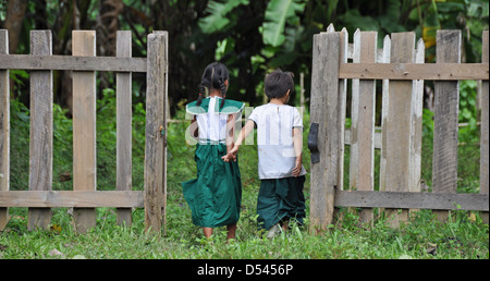 two children, boy and girl, walk away from camera hand in hand Photographed in Myanmar, Hsipaw Stock Photo