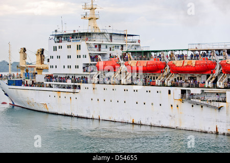 Tug Assisting the Nicobar Ferry From Mumbai,India calling at Port Blair packed with Passengers from the mainland,Andaman Islands Stock Photo