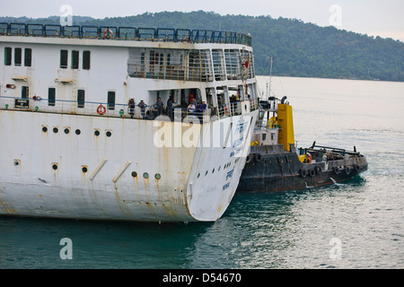 Tug Assisting the Nicobar Ferry From Mumbai,India calling at Port Blair packed with Passengers from the mainland,Andaman Islands Stock Photo