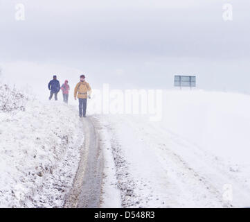 English Peak District, Derbyshire, UK. 24th March 2013. Hikers walking alongside the A621 between Baslow and Sheffield which is covered in snow. Heavy snow and high winds were causing drifting snow to block the road. Credit: eye35/Alamy Live News Stock Photo