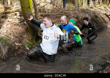 Kilmarnock, UK. 24 March 2013. Organised Mud Run at Craufurdland Castle Estate, near Kilmarnock.  Despite the recent bad weather approximately 200 Mud Runners took part in the annual run across the estate. The route was over 10 kilometres through woodlands, across rivers and water filled ditches Many of the runners were being sponsored for charities. Stock Photo