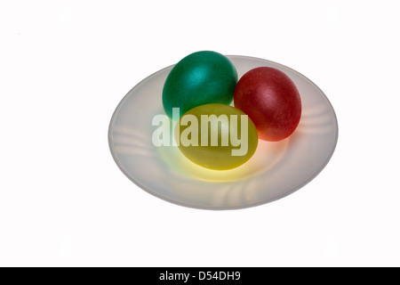 Red, green and yellow Easter eggs on a plate isolated against white background Stock Photo