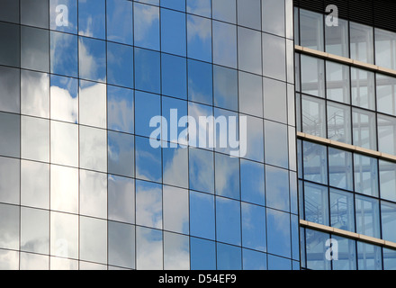 reflective windows on side of modern office building with clouds and sky Stock Photo