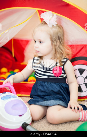 Happy little child playing with vacuum cleaner toy in domestic room Stock Photo