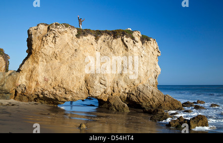 Man with arms raised atop formation at El Matador State Beach in Southern California Stock Photo