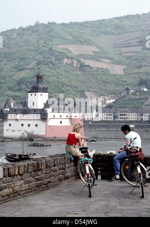 a couple of cyclists stop for lunch along the Rhine river valley at Burg Pfalz Castle in Kaub Germany Stock Photo