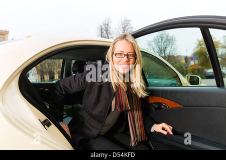 Young woman getting out of taxi, she has reached her destination Stock Photo