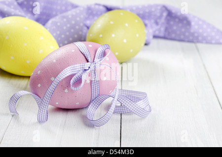 Easter eggs with violet ribbon on white wooden background Stock Photo