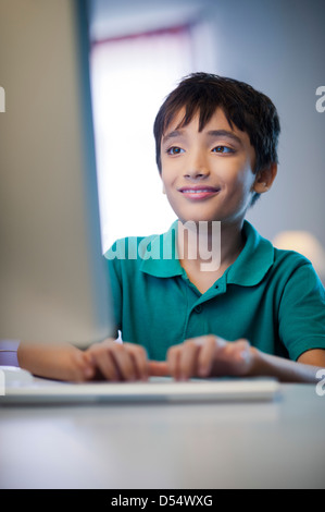 Boy using a desktop pc and smiling at home Stock Photo