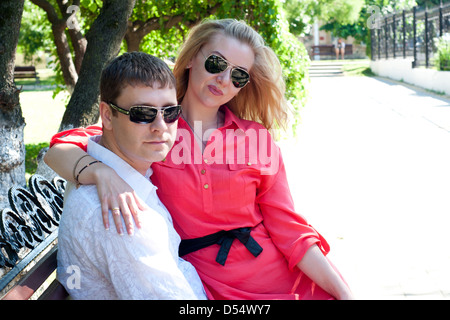 the young couple sits on a bench in a summer garden Stock Photo