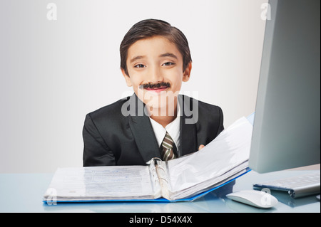 Boy imitating like businessman smiling while examining documents Stock Photo