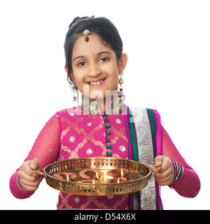 Girl imitating like woman holding oil lamps and smiling on diwali Stock Photo