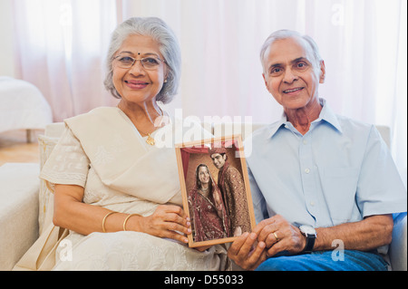 Senior couple holding a wedding photograph and smiling Stock Photo