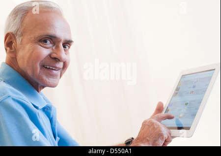 Portrait of a senior man using a digital tablet and smiling Stock Photo