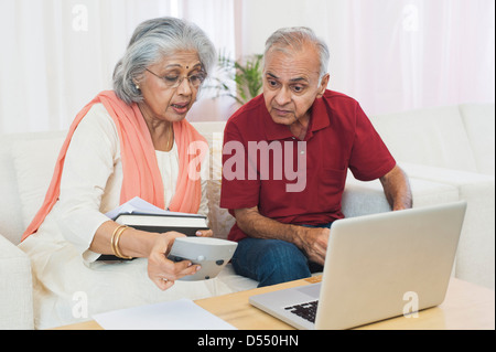 Senior couple sitting in front of a laptop checking bills Stock Photo
