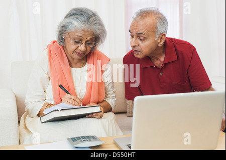 Senior couple sitting in front of a laptop checking bills Stock Photo