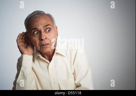 Man cupping hand to ear Stock Photo