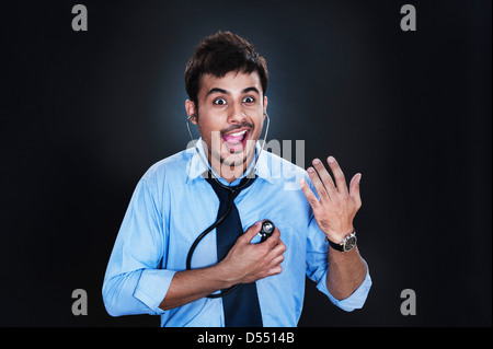 Close-up of a businessman listening to his heartbeat with stethoscope and making a face Stock Photo