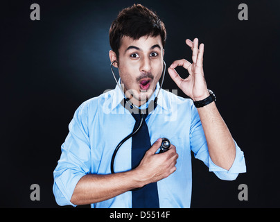 Close-up of a businessman listening to his heartbeat with stethoscope and showing ok sign Stock Photo