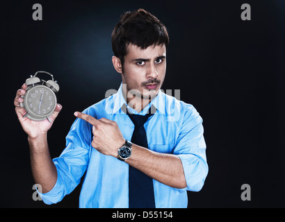 Angry businessman pointing towards an alarm clock Stock Photo