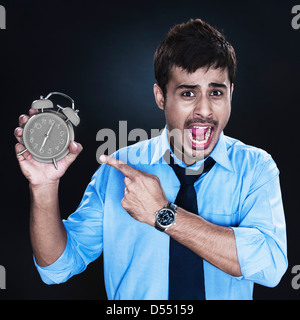 Angry businessman pointing towards an alarm clock Stock Photo