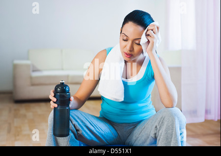 Woman sitting on a fitness ball wiping her sweat Stock Photo