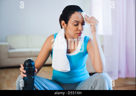 Woman sitting on a fitness ball wiping her sweat Stock Photo