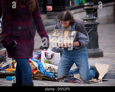 Homeless man begging for money using a sign, in the city centre of Brussels, Belgium Stock Photo