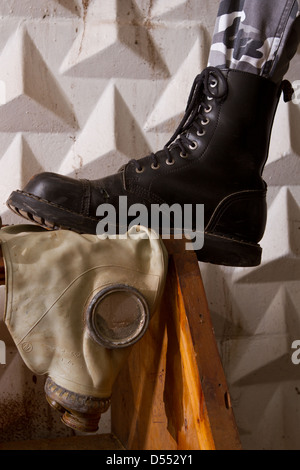 black army boots standing on gas mask in an abandoned basement Stock Photo