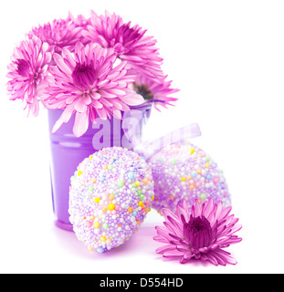 Beautiful Easter still life isolated on white background, decorated chicken eggs, fresh pink flowers in purple bucket Stock Photo