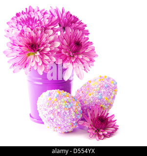 Easter eggs decorated with colors beads, fresh pink gerbera flowers in violet pot, isolated on white background, spring holidays Stock Photo