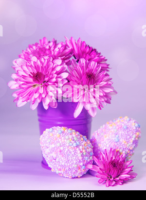 Traditional Easter symbol, chicken eggs with colorful decorations and fresh flowers in vase isolated on pink background Stock Photo
