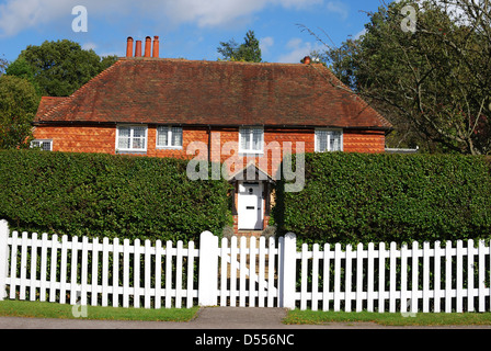 Tiled and brick cottage behind picket fence at Chiddingfold. Surrey. England Stock Photo