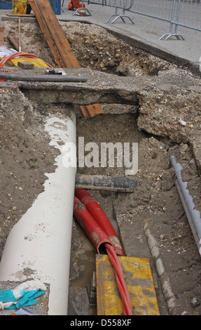 digging for roadworks during the laying of a conduit for fiber optic and electric cables Stock Photo