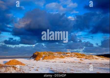 Snow covered dunes and Sunset at Holkham beach National nature reserve Norfolk Stock Photo