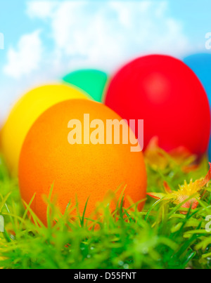 Beautiful painted colorful eggs on fresh green grass over blue sky, happy Easter holiday, religious traditions, spring nature Stock Photo