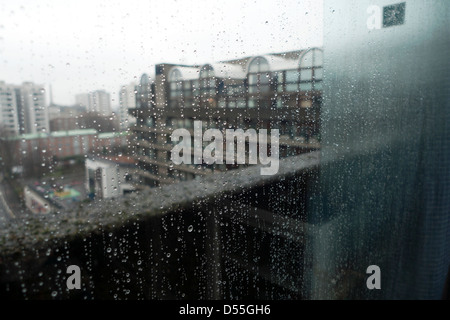 Raindrops on a window looking out from inside of a Barbican Estate flat on a dismal hostile rainy winter day in the City of London UK  KATHY DEWITT Stock Photo