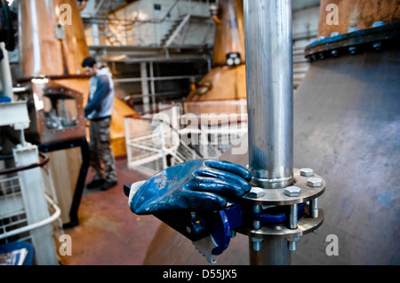 Rubber gloves lie on machinery with operator in background Stock Photo