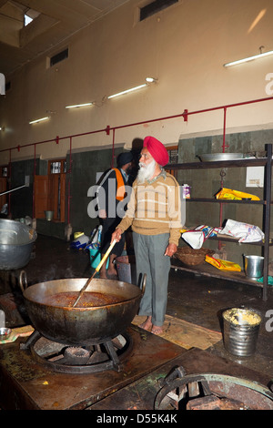 A Sikh volunteer cooking chickpeas in a large karahi at the free kitchen inside the Golden Temple complex Amritsar Punjab India Stock Photo