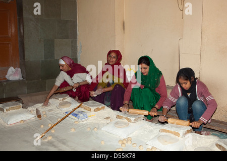 Four women making chapattis in the kitchens of  the Golden Temple complex at Amritsar Punjab India Stock Photo