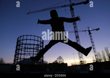 Berlin, Germany, Silhouette, Boy makes a leap into the air in front of the Gasometer Schoeneberg Stock Photo