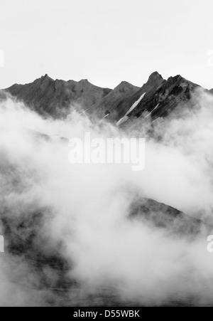 Black and white view of low clouds, mist and fog partially obscure the Alaska Range, Denali National Park, Alaska, USA Stock Photo
