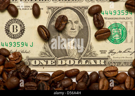 A a dollar bill is covered with coffee beans in Berlin, Germany, 28 October 2010. About 50 countries in the world cultivate coffee at the moment. The coffee plant's country of origin is held to be Ethiopia. Slave traders brought the berries from the coffee plant with them to Arabia in the 14th century. Photo: Soeren Stache Stock Photo