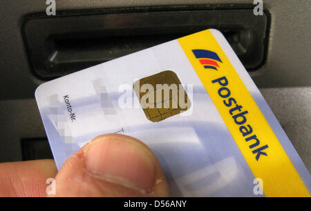 (dpa file) A file picture dated 07 February 2008 of a hand putting a cash card into an ATM in Essen, Germany. German Postbank presents its financial figures for Q3 of 2010 on 11 November 2010. Photo: Franz-Peter Tschauner Stock Photo