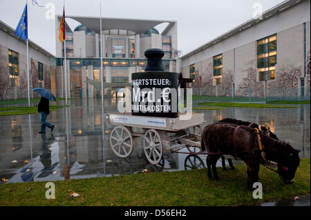 A mule (front) and a donkey carry signs with the VAT (value added tax)  rates of 7 and 19 percent and draw a carriage with a weight saying 'VAT: 14 billion bureaucratic costs' in front of the Chancellery in Berlin, Germany, 18 November 2010. The purchase of a donkey has to include 19 percent VAT while the purchase of a mule includes a mere 7 percent. An citizen's initiative urges t Stock Photo