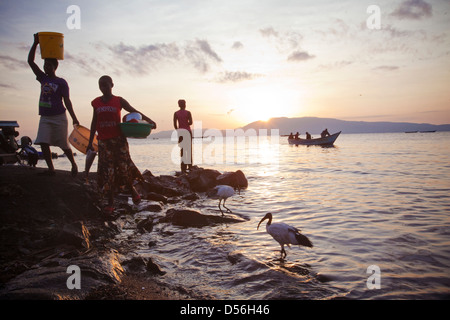 Women at sunrise returning from cleaning pots and pans, Remba Island, Lake Victoria, Kenya. Stock Photo