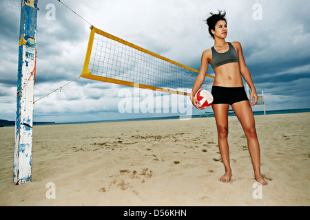 Mixed race woman holding volleyball on beach Stock Photo