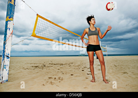 Mixed race woman playing with volleyball on beach Stock Photo