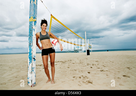 Mixed race woman holding volleyball on beach Stock Photo