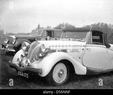 Historical 1950s, Two cars from this era parked beside each other in a field at a racecourse, one a luxury saloon, possibly a Bentley, the other, a two-seater, open-top sportscar with distinctive shaped engine grill, England, UK. Stock Photo